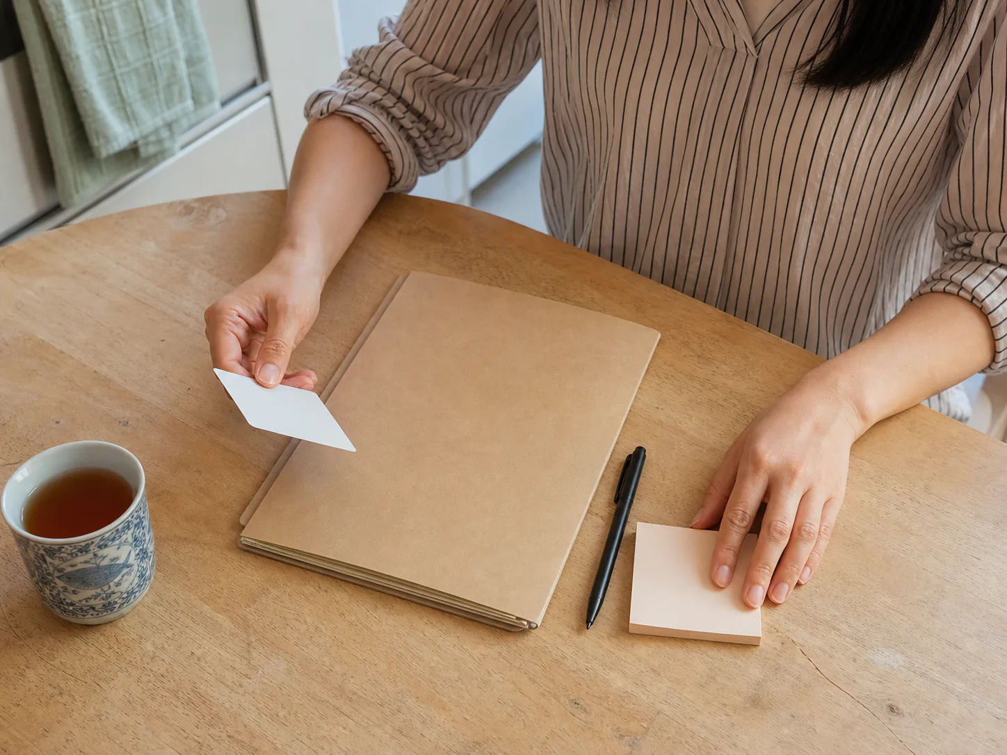 Padre de familia en la mesa de la cocina sosteniendo una tarjeta del seguro junto a una carpeta de documentos