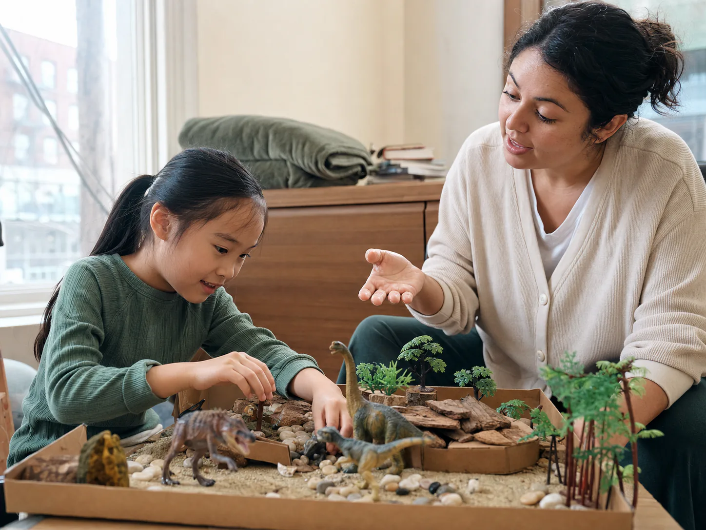 Niña compartiendo su interés por los dinosaurios mientras su terapeuta sigue su iniciativa